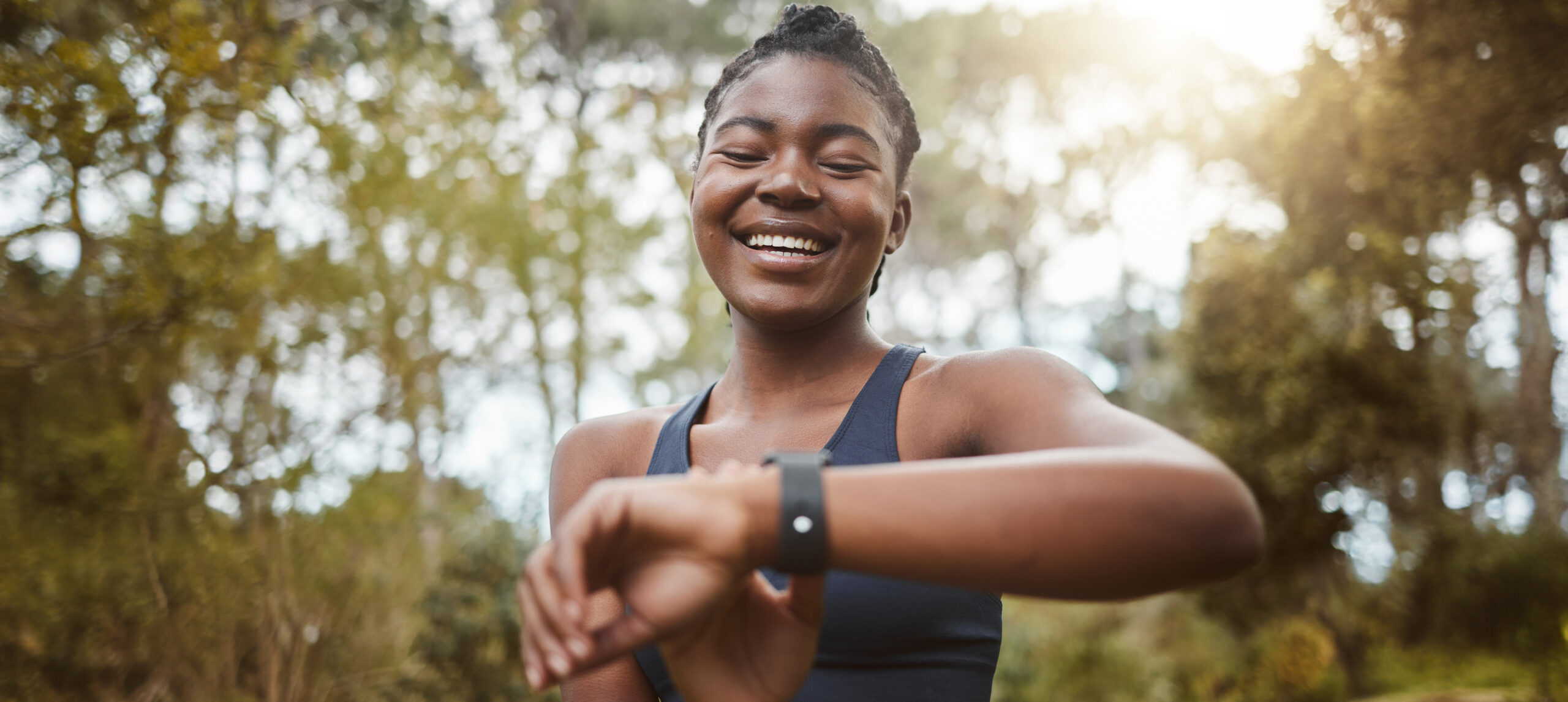 African runner woman, smart watch and park for check, smile or happy for time, results or fitness in nature. Girl, iot clock and monitor for speed, heart rate or smile for exercise, workout or health stock photo