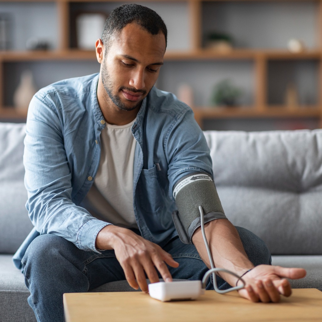 man using at-home blood pressure cuff as part of remote patient monitoring